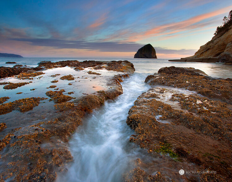 A surge of water blasts into a narrow channel in the surf zone near Cape Kiwanda, Oregon. Cape Kiwanda is well known for its...