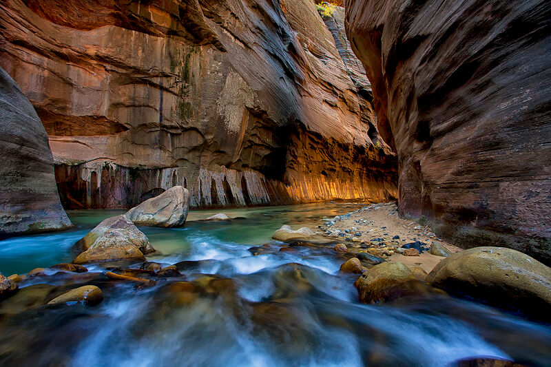 The warm glow reflects off the distant canyon wall deep inside the Narrows of Zion National Park.